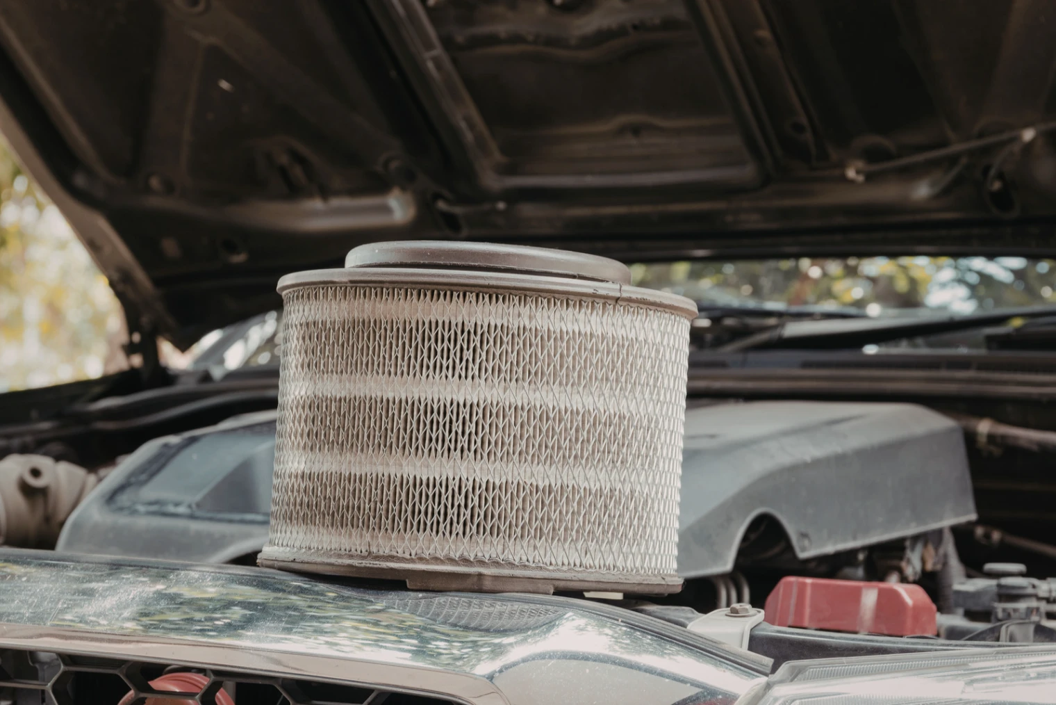 air filter of car - Warringah Brake & Clutch Centre – Clutches, Brakes, Rotors Cylindrical automotive air filter with metal mesh sits atop an open car hood in the engine bay.